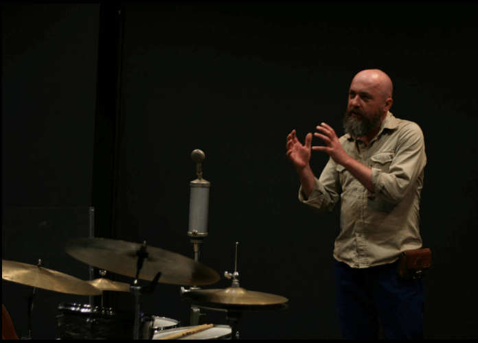 Mężczyzna objaśnia technikę gry na perkusji.