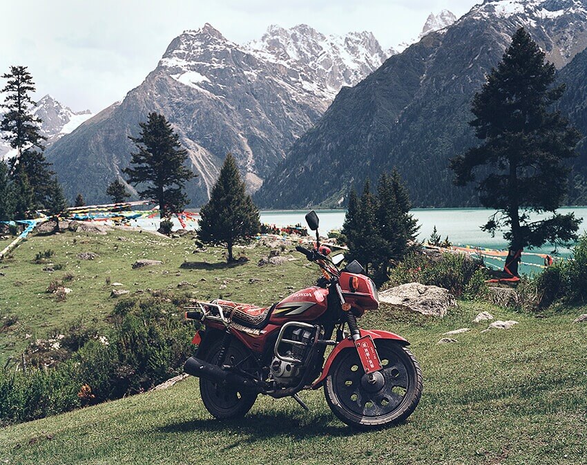 Czerwony motocykl na tle szczytów górskich.